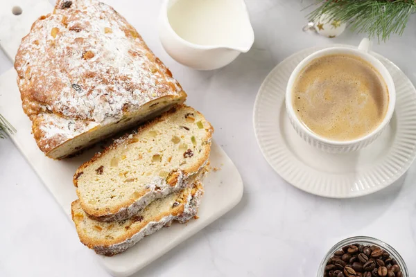 Beyaz çay tabağında kahve kapuçino ve mermer bir masada çalınmış noel pastası.