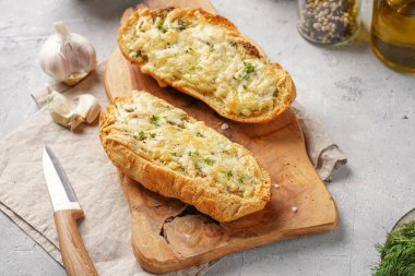 İki parça sarımsaklı ve tereyağlı ekmek - tahtanın üzerinde baget, deniz tuzu, biber, dereotu ve sarımsak karanfili gri beton arka planda, üst manzara