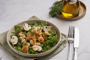 Karides ve şampiyon Arugula salatası, beyaz bir yüzeyde ahşap bir tahtada zeytin yağı ve dereotu.