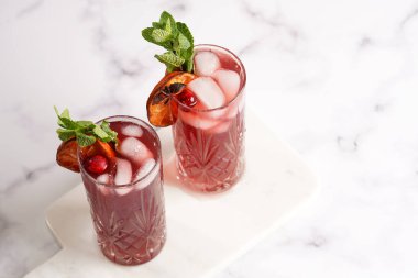 Geleneksel noel içeceği kırmızı kiraz suyu, portakal mandalinası, tarçın çubuğu, buz küpleri ve mermer tahtada anason soslu şarap.