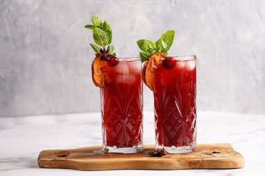 Geleneksel noel içeceği kırmızı kiraz suyu, portakal mandalinası, tarçın çubuğu, buz küpleri ve ahşap tahta üzerinde anason.