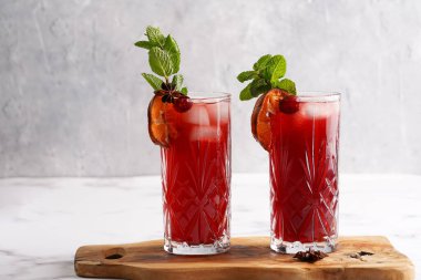 Geleneksel noel içeceği kırmızı kiraz suyu, portakal mandalinası, tarçın çubuğu, buz küpleri ve ahşap tahta üzerinde anason.