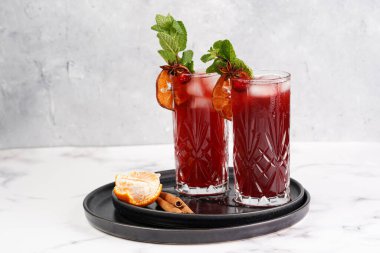 Geleneksel Noel içeceği kırmızı kiraz suyu, portakal mandalinası, tarçın çubuğu, buz küpleri ve siyah tepsilerde anason içeren sıcak şarap.