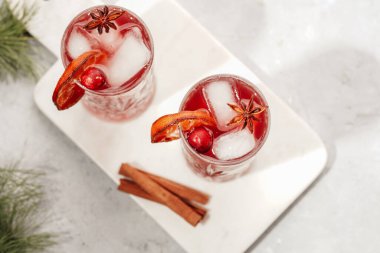 Geleneksel Noel içeceği kırmızı kiraz suyu, portakal mandalinası, tarçınlı çubuk, buz küpü ve anason, üst manzara, yakın çekim.