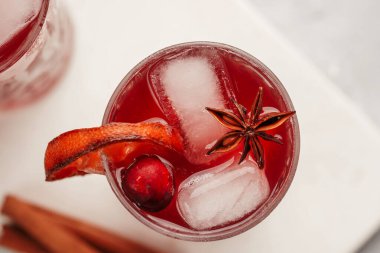 Geleneksel Noel içeceği kırmızı kiraz suyu, portakal mandalinası, tarçınlı çubuk, buz küpü ve anason, üst manzara, yakın çekim.