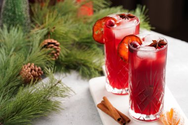 Geleneksel noel içeceği kırmızı kiraz suyu, portakal mandalinası, tarçın çubuğu, buz küpleri ve mermer bir tahtanın üzerinde anason.
