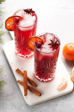Geleneksel noel içeceği kırmızı kiraz suyu, portakal mandalinası, tarçın çubuğu, buz küpleri ve mermer bir tahtanın üzerinde anason.