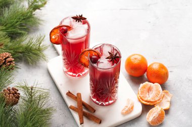 Geleneksel noel içeceği kırmızı kiraz suyu, portakal mandalinası, tarçın çubuğu, buz küpleri ve mermer bir tahtanın üzerinde anason.