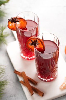 Geleneksel noel içeceği kırmızı kiraz suyu, portakal mandalinası, tarçın çubuğu ve mermer bir tahtanın üzerinde anason.