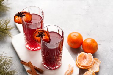 Geleneksel noel içeceği kırmızı kiraz suyu, portakal mandalinası, tarçın çubuğu ve mermer bir tahtanın üzerinde anason.
