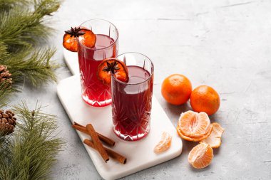 Geleneksel noel içeceği kırmızı kiraz suyu, portakal mandalinası, tarçın çubuğu ve mermer bir tahtanın üzerinde anason.