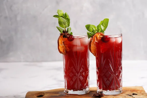 Geleneksel noel içeceği kırmızı kiraz suyu, portakal mandalinası, tarçın çubuğu, buz küpleri ve ahşap tahta üzerinde anason.