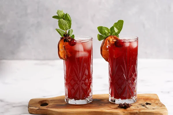 Geleneksel noel içeceği kırmızı kiraz suyu, portakal mandalinası, tarçın çubuğu, buz küpleri ve ahşap tahta üzerinde anason.