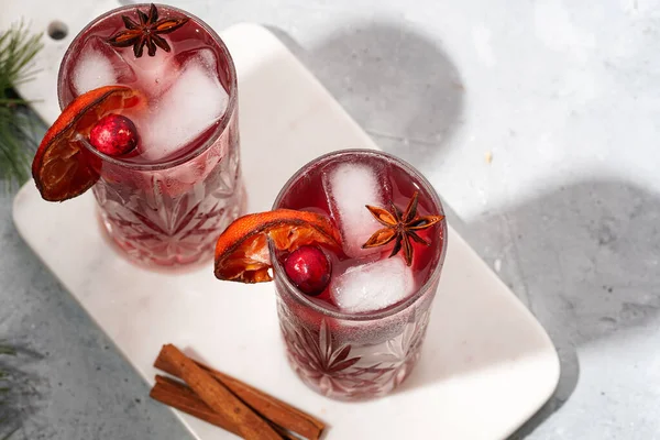 Geleneksel Noel içeceği kırmızı kiraz suyu, portakal mandalinası, tarçınlı çubuk, buz küpü ve anason, üst manzara, yakın çekim.