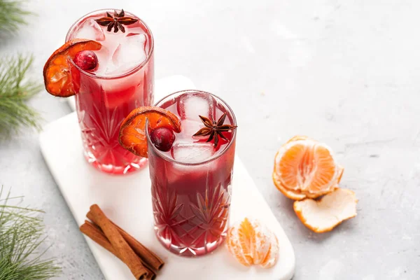 Geleneksel noel içeceği kırmızı kiraz suyu, portakal mandalinası, tarçın çubuğu, buz küpleri ve mermer bir tahtanın üzerinde anason.