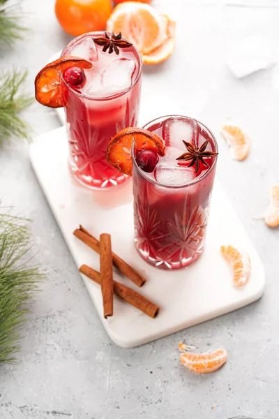 Geleneksel noel içeceği kırmızı kiraz suyu, portakal mandalinası, tarçın çubuğu, buz küpleri ve mermer bir tahtanın üzerinde anason.