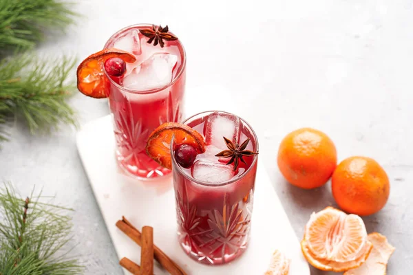 Geleneksel noel içeceği kırmızı kiraz suyu, portakal mandalinası, tarçın çubuğu, buz küpleri ve mermer bir tahtanın üzerinde anason.