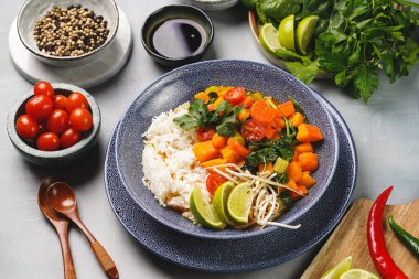 Kırmızı Tayland baharatlı sebze ve basmati pilavı, taze limon, kişniş, ıspanak, kırmızı biber ve kiraz domatesli mavi kase.