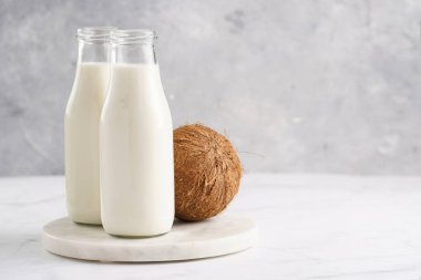 Sütsüz iki şişe süt ve mermer tahtada hindistan cevizi.