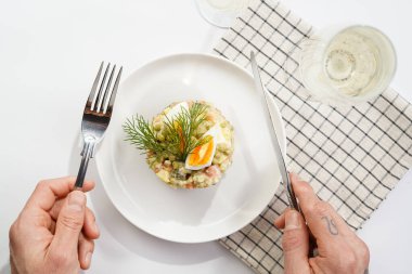 Male hand holding silver fork and knife over a traditional east european dish for New Year's Eve - salad 