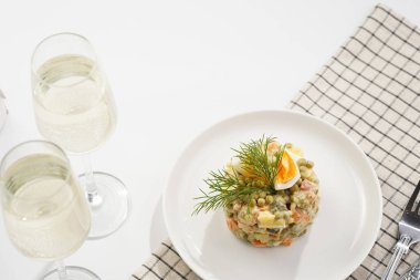 Yeni yıl arifesi için geleneksel Doğu Avrupa yemeği - patates, havuç, soğan, bezelye, sosis, salatalık, yumurta ve beyaz tabakta mayonez salatası 