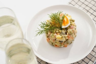 Yeni yıl arifesi için geleneksel Doğu Avrupa yemeği - patates, havuç, soğan, bezelye, sosis, salatalık, yumurta ve beyaz tabakta mayonez salatası 