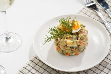 Yeni yıl arifesi için geleneksel Doğu Avrupa yemeği - patates, havuç, soğan, bezelye, sosis, salatalık, yumurta ve beyaz tabakta mayonez salatası 