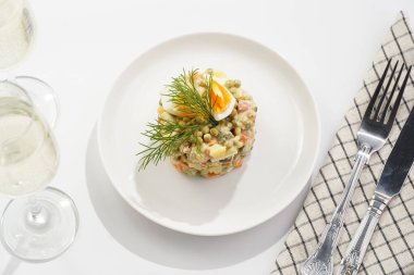 Yeni yıl arifesi için geleneksel Doğu Avrupa yemeği - patates, havuç, soğan, bezelye, sosis, salatalık, yumurta ve beyaz tabakta mayonez salatası 