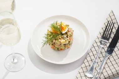 Yeni yıl arifesi için geleneksel Doğu Avrupa yemeği - patates, havuç, soğan, bezelye, sosis, salatalık, yumurta ve beyaz tabakta mayonez salatası 