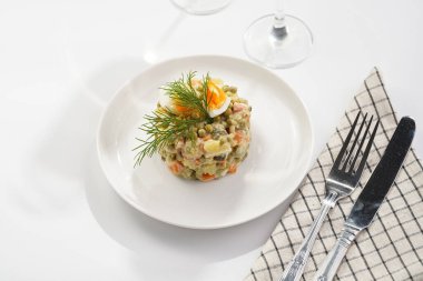 Yeni yıl arifesi için geleneksel Doğu Avrupa yemeği - patates, havuç, soğan, bezelye, sosis, salatalık, yumurta ve beyaz tabakta mayonez salatası 