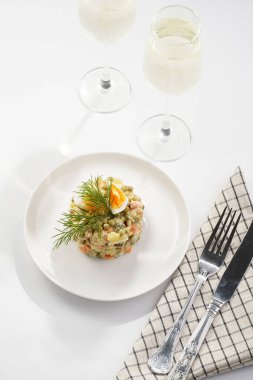 Yeni yıl arifesi için geleneksel Doğu Avrupa yemeği - patates, havuç, soğan, bezelye, sosis, salatalık, yumurta ve beyaz tabakta mayonez salatası 