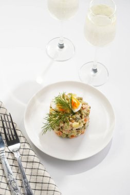 Yeni yıl arifesi için geleneksel Doğu Avrupa yemeği - patates, havuç, soğan, bezelye, sosis, salatalık, yumurta ve beyaz tabakta mayonez salatası 