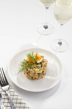 Yeni yıl arifesi için geleneksel Doğu Avrupa yemeği - patates, havuç, soğan, bezelye, sosis, salatalık, yumurta ve beyaz tabakta mayonez salatası 