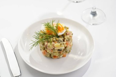 Yeni yıl arifesi için geleneksel Doğu Avrupa yemeği - patates, havuç, soğan, bezelye, sosis, salatalık, yumurta ve beyaz tabakta mayonez salatası 