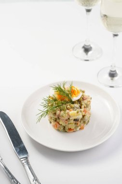 Yeni yıl arifesi için geleneksel Doğu Avrupa yemeği - patates, havuç, soğan, bezelye, sosis, salatalık, yumurta ve beyaz tabakta mayonez salatası 