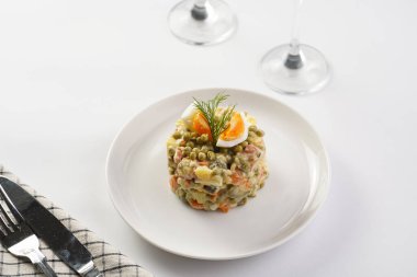 Yeni yıl arifesi için geleneksel Doğu Avrupa yemeği - patates, havuç, soğan, bezelye, sosis, salatalık, yumurta ve beyaz tabakta mayonez salatası 