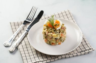 Yeni yıl arifesi için geleneksel Doğu Avrupa yemeği - patates, havuç, soğan, bezelye, sosis, salatalık, yumurta ve beyaz tabakta mayonez salatası 