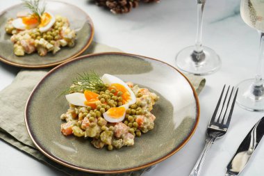 Yeni yıl arifesi için geleneksel Doğu Avrupa yemeği - patates, havuç, soğan, bezelye, sosis, salatalık, yumurta ve yeşil tabakta mayonez ile 