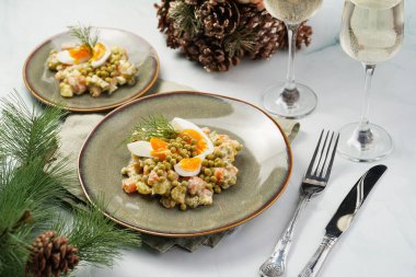 Yeni yıl arifesi için geleneksel Doğu Avrupa yemeği - patates, havuç, soğan, bezelye, sosis, salatalık, yumurta ve yeşil tabakta mayonez ile 