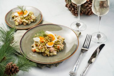Yeni yıl arifesi için geleneksel Doğu Avrupa yemeği - patates, havuç, soğan, bezelye, sosis, salatalık, yumurta ve yeşil tabakta mayonez ile 