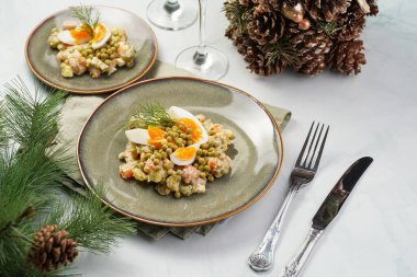Yeni yıl arifesi için geleneksel Doğu Avrupa yemeği - patates, havuç, soğan, bezelye, sosis, salatalık, yumurta ve yeşil tabakta mayonez ile 