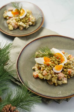 Yeni yıl arifesi için geleneksel Doğu Avrupa yemeği - patates, havuç, soğan, bezelye, sosis, sosis ve yeşil tabakta mayonez ile salata 