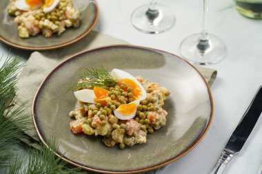 Yeni yıl arifesi için geleneksel Doğu Avrupa yemeği - patates, havuç, soğan, bezelye, sosis, sosis ve yeşil tabakta mayonez ile salata 