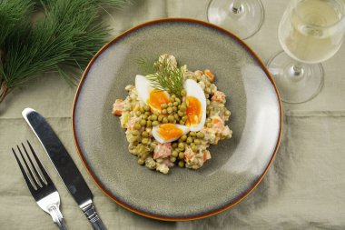 Yeni yıl arifesi için geleneksel Doğu Avrupa yemeği - patates, havuç, soğan, bezelye, sosis, sosis ve yeşil tabakta mayonez ile salata 