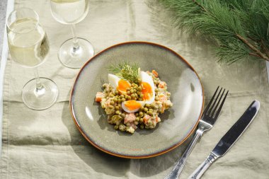 Yeni yıl arifesi için geleneksel Doğu Avrupa yemeği - patates, havuç, soğan, bezelye, sosis, sosis ve yeşil tabakta mayonez ile salata 