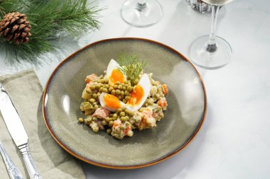 Yeni yıl arifesi için geleneksel Doğu Avrupa yemeği - patates, havuç, soğan, bezelye, sosis, sosis ve yeşil tabakta mayonez ile salata 