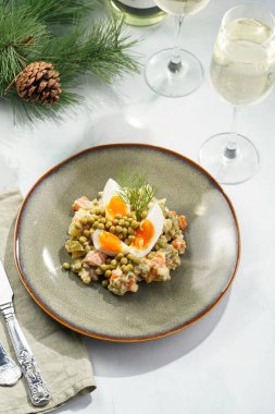 Yeni yıl arifesi için geleneksel Doğu Avrupa yemeği - patates, havuç, soğan, bezelye, sosis, sosis ve yeşil tabakta mayonez ile salata 