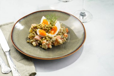 Yeni yıl arifesi için geleneksel Doğu Avrupa yemeği - patates, havuç, soğan, bezelye, sosis, sosis ve yeşil tabakta mayonez ile salata 