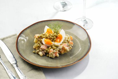 Yeni yıl arifesi için geleneksel Doğu Avrupa yemeği - patates, havuç, soğan, bezelye, sosis, sosis ve yeşil tabakta mayonez ile salata 