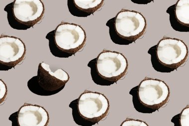 Gri bir arka planda çatlak bir hindistan cevizinin sert, güneşli, pürüzsüz deseni.